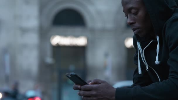 路上で孤独な黒人アフリカ系移民 スマートフォンで入力 スローモーション — ストック動画