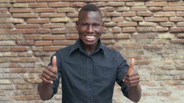 gülümseyen mutlu genç afrikalı-amerikalı adam başparmak gösteren. Kazanmak, başarı