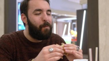 Çekici bir adam hamburger ısırma ve tat-kapanış kadar tadını çıkarın