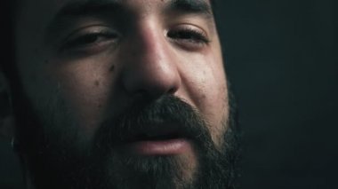 Karanlık kameraya bakarak ağlayan üzgün sakallı adam