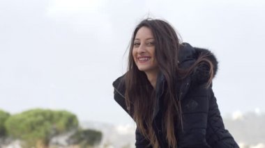 korkuluk üzerinde oturan rahat genç kadın portresi etrafında döner ve kamera gülümsüyor