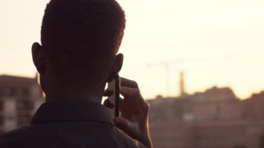 Siyah amrican adam telefon la konuşurken odaklanmak şehir-geri görünümü bakarak