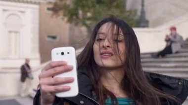 Güzel şehvetli genç kadın rüzgarlı bir gün selfie alarak-şehir arka plan