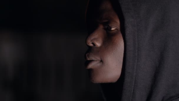 Karanlıkta Kapüşonlu Siyah Adam Dönüm Kameraya Bakıyor — Stok video