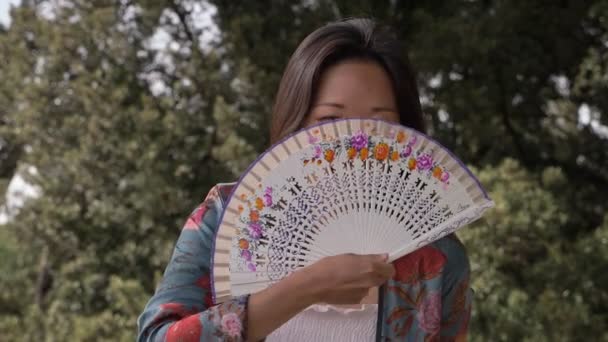 Sonriente Feliz Asiático Mujer Cubrir Cara Con Ventilador Parque — Vídeos de Stock