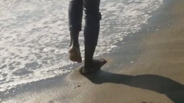 özgürlük, doğa, rahatla. siyah adamın bacakları sahilde yürüyor