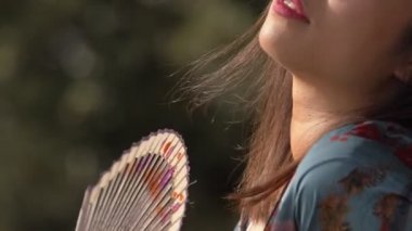 yaz, sıcak, dalga. Asyalı kadın park yavaş hareket fan kullanarak