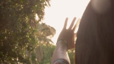 young woman protects herself from sunlight with her hand - slow motion