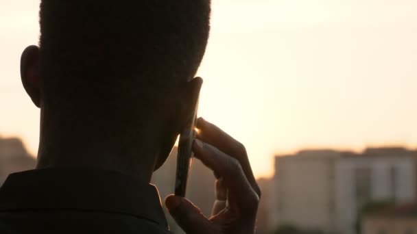 Zwarte Amerikaanse Man Praten Telefonisch Observeren Van Stad Zonsondergang Back — Stockvideo
