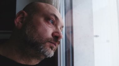 pencereye yaslanmış düşünceli üzgün adam yakın portarit, dışarı bakarak