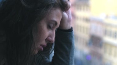 Üzgün genç kadın pencerede yalnız