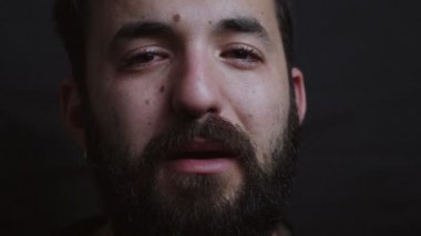 kameraya bakarak karanlıkta ağlayan Üzgün sakallı adamın yakın portresi