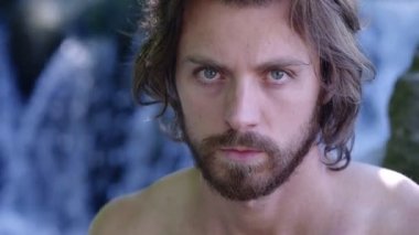 şelale yakınında kameraya bakan Ciddi çekici adam yakın. Doğa, vahşi,