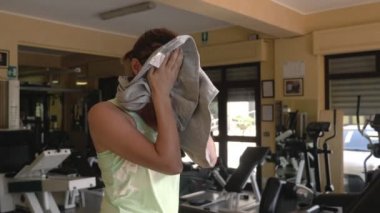 koşu bandıüzerinde yorgun kadın bir havlu ile yüzünü kurutma.çaba, fitness, egzersiz