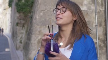 Mutlu çekici genç kadın kokteyl içme, sokak yavaş hareket gülümseyerek