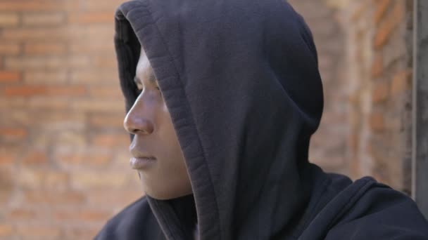 フードの回転とカメラを見つめて深刻な若いアフリカの移民 — ストック動画