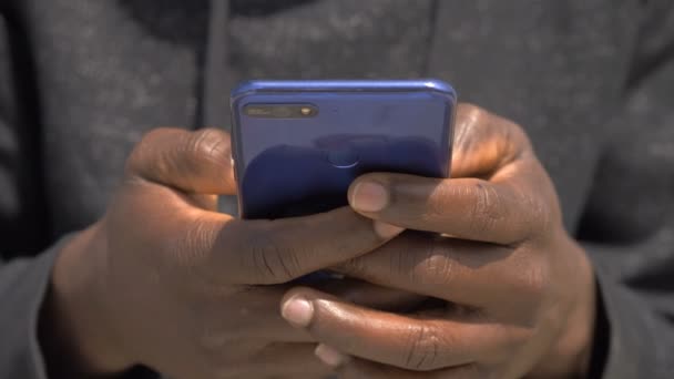 黒人男性はスマートフォンでタイピングを手にします 近代性 コミュニケーション — ストック動画