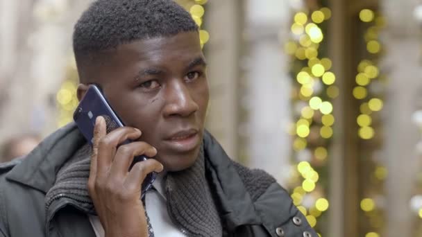 アフリカ系アメリカ人の男が街でスマートフォンを使ってる 通信してるハンサムな若い男 — ストック動画