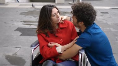 Handikap, aşk, romantizm. Tekerlekli sandalyedeki genç kadın çekici bir adamla flört ediyor.