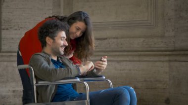 Engelli arkadaşıyla şehirdeki akıllı telefonlara bakan bir kadın.