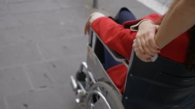 Genç adam çekici arkadaşını tekerlekli sandalyeye itiyor.