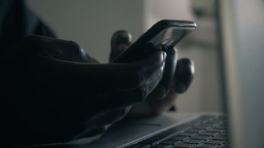 Siyah adamın eli akıllı telefonda daktilo ediyor.