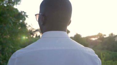 Kendine güvenen, yalnız, genç bir zenci şehirde günbatımının tadını çıkarıyor.