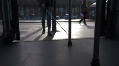 Genç kör kadın beyaz bastonuyla otobüse biniyor.