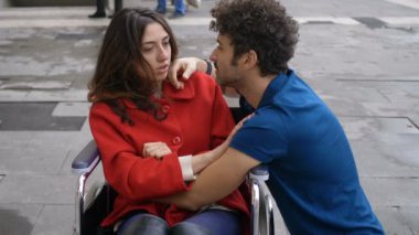 Handikap, aşk, romantizm. Tekerlekli sandalyedeki genç kadın çekici bir adamla flört ediyor.