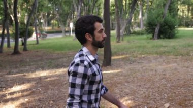Parkta sakallı ve esmer saçlı genç adam.