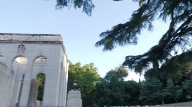 Şehirdeki mermer bir balkonda oturan zarif kadın manzaraya bakıyor.