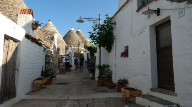Alberobello sokaklarında sabit kamera var. Cerrahi maske takan turistler Trulli 'ye hayran. 