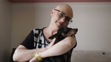 Teselli, şefkat - Kemoterapi aldıktan sonra gülümseyen kel kadının portresi ve köpeğini okşaması.