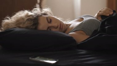 Uyuyan genç kadın, çalan cep telefonuyla uyanır.