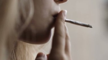  Bir sigarayı hevesle emen genç bir kadının ağır ağır konuşması.