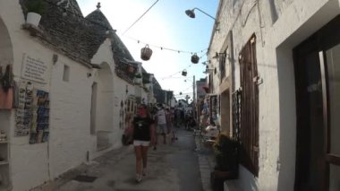Coronavirüs zamanında turizm - cerrahi maske takan insanlar Alberobello 'nun trullisine hayran kalıyorlar, tipik koni şekilli yapılar, puglia, Ağustos 2020