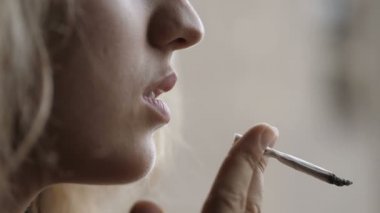 Yakından bakınca güzel bir kadın sigara içiyor. Yavaş çekimde.