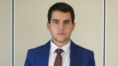 Ameliyat maskesi takan genç işadamı kameraya bakıyor.