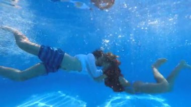 Genç bir çiftin havuzda öpüştüğü su altı çekimleri.