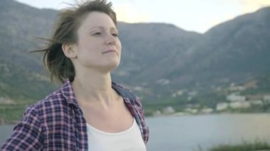 Okyanusa bakarak bir adada bir uçurumun üstünde duran genç kadın. Günbatımı