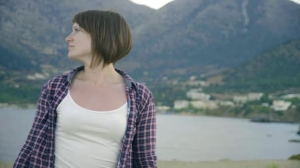 Jonge vrouw stond op de top van een klif op een eiland te kijken naar de Oceaan. Zonsondergang — Stockvideo