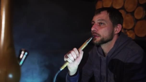 Man smokes hookah in a bar. — Stock Video