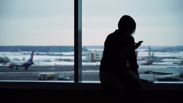 Mulher no terminal do aeroporto aguardando voo usando smartphone — Vídeo de Stock