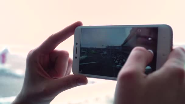 Vrouw in luchthaven terminal afwachting vlucht neemt foto's op een smartphone. — Stockvideo