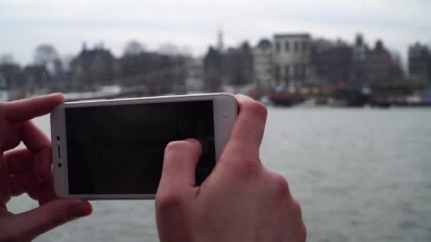 Девушка плавает на лодке по каналам в Амстердаме и фотографирует по телефону — стоковое видео