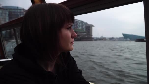 Girl sail on a boat through the canals in Amsterdam and looks out the window. — Stock Video