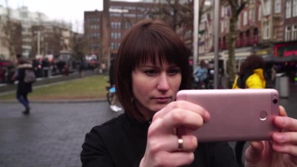 Vrouw toeristische neemt pictureson op smartphone de stad. Rembrandtplein in Amsterdam. Slow motion — Stockvideo