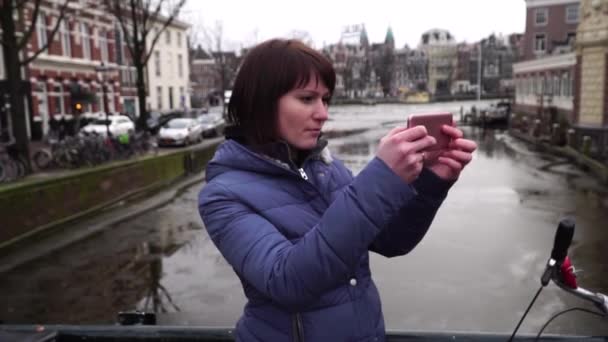 Turista mujer toma fotos en el teléfono inteligente de la ciudad. Amsterdam. cámara lenta — Vídeos de Stock