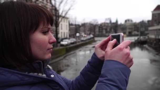 女性観光客は、アムステルダムでのスマート フォンの pictureson. — ストック動画