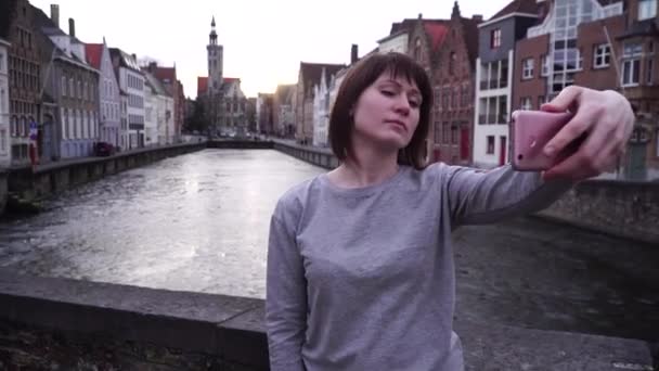 Turista menina faz selfi em um smartphone em um fundo da cidade de Bruges Bélgica — Vídeo de Stock
